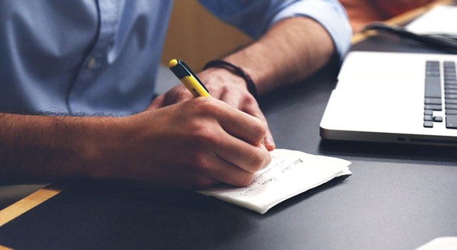 Man Writing Content in Notebook